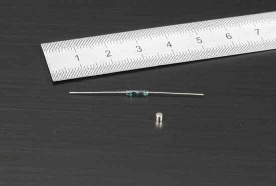 A small reed switch (MITI-7-15-20 de Littelfuse) and a tiny magnet able to trigger it 